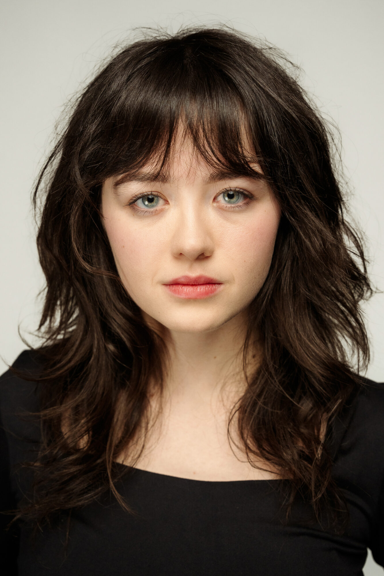 Portret młodej kobiety. Włosy ciemnobrązowe, grzywka zasłania czoło. Oczy duże, zaróżowione policzki, niewielkie usta.